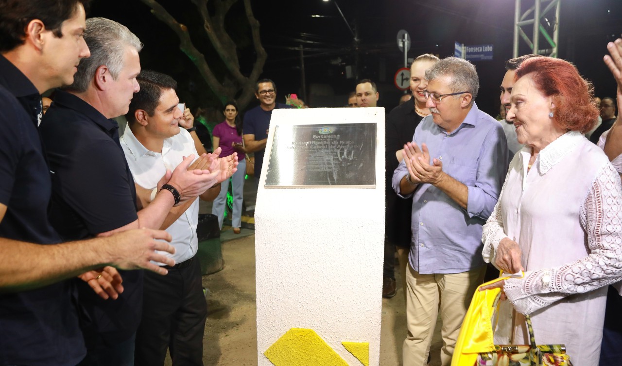 grupo de pessoas descerra a placa da praça